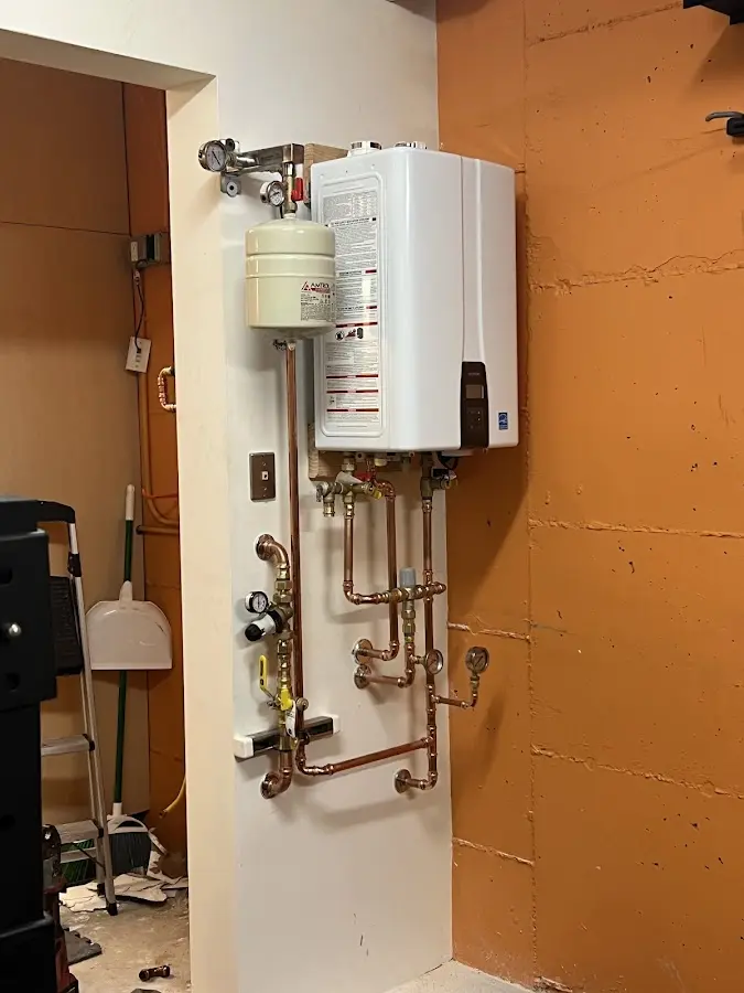 Plumbing technician inspecting water heater connections in Jena